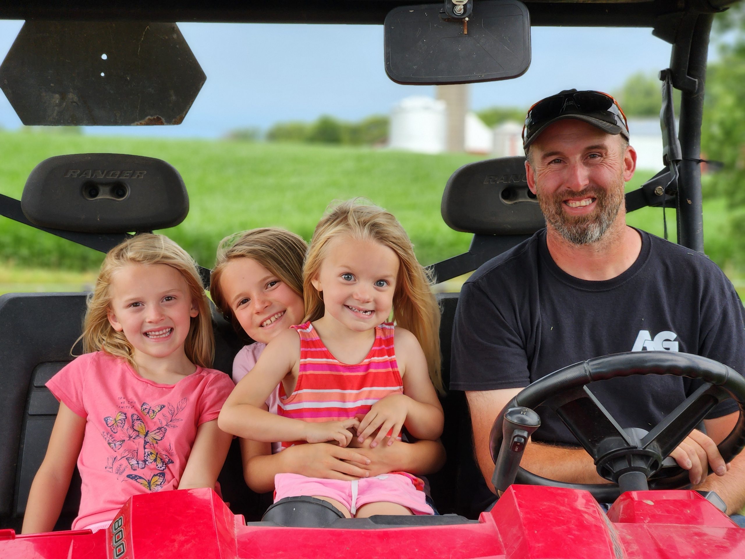 Dwyer kids riding to the field with their dad for a harvest ride-along on their family farm.