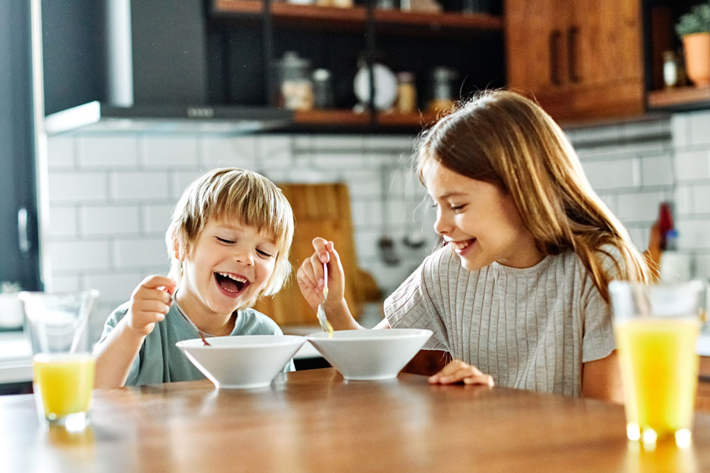 Photo of two children smiling and eating cereal